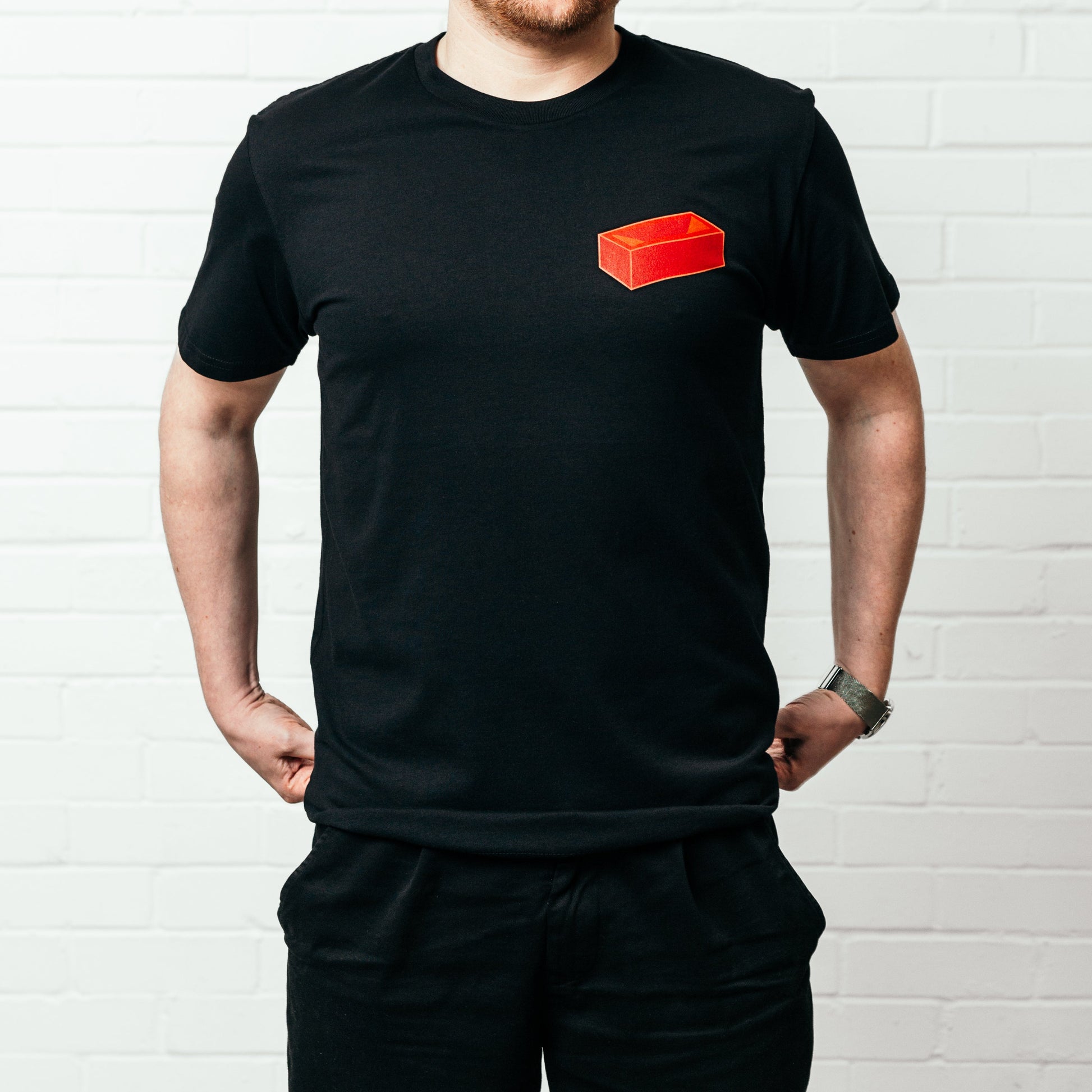 A man wearing a black t-shirt with a red brick on it.